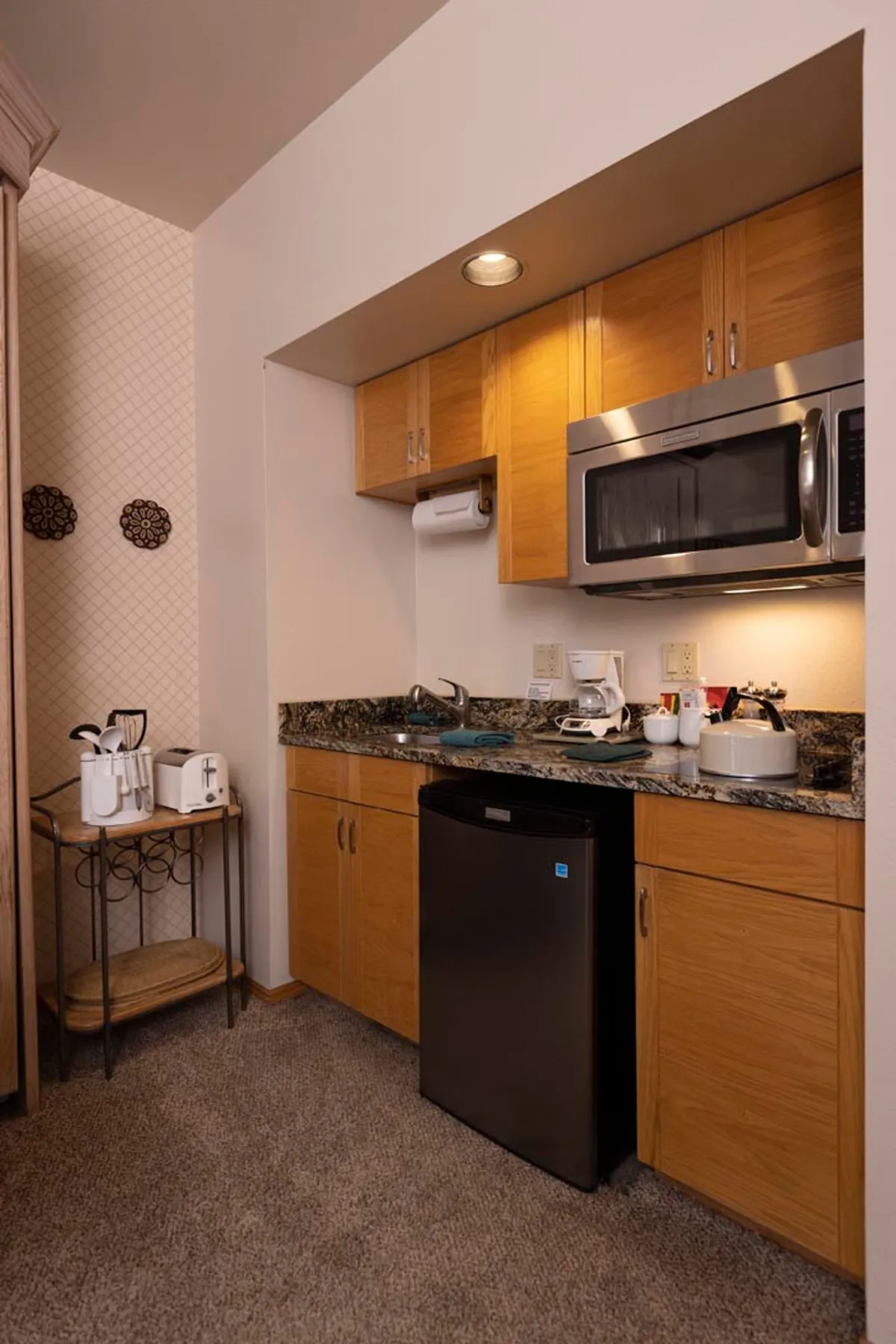 The image presents a compact kitchenette area with a granite countertop, microwave, mini fridge, and various kitchen accessories. While not a direct sleeping space, it hints at the comfort and self-sufficiency of the living area, showing how guests can enjoy meals or snacks in the same multi-use environment.