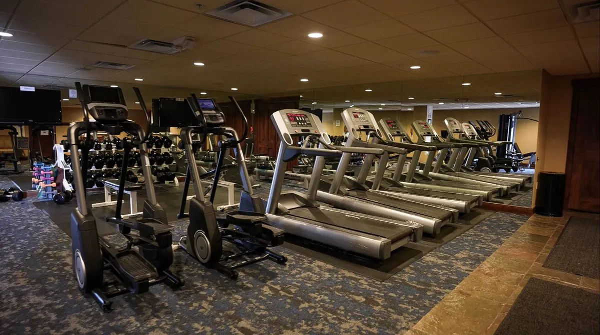 This interior shot features a well-equipped fitness center, complete with treadmills, ellipticals, free weights, and large mirrors. The space appears modern, clean, and filled with natural light, motivating guests to keep active during their stay.