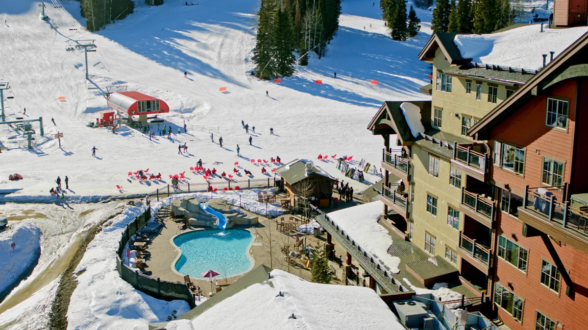 This festive exterior scene highlights ski slopes bustling with skiers and snowboarders, a pool area for relaxation, and the unique architecture of the resort buildings. It conveys an atmosphere of activity, relaxation, and year-round entertainment right outside your door.