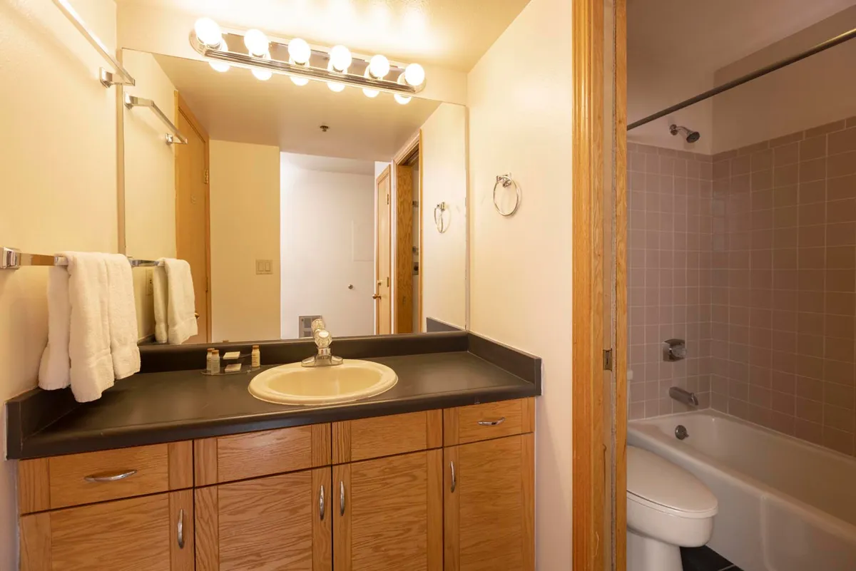 The image displays a stylish bathroom with a large vanity, mirror, and modern shower area. The space appears practical and relaxing, ideal for starting the day refreshed or unwinding after outdoor excursions. Subtle decor and clean lines enhance the sense of comfort and convenience.