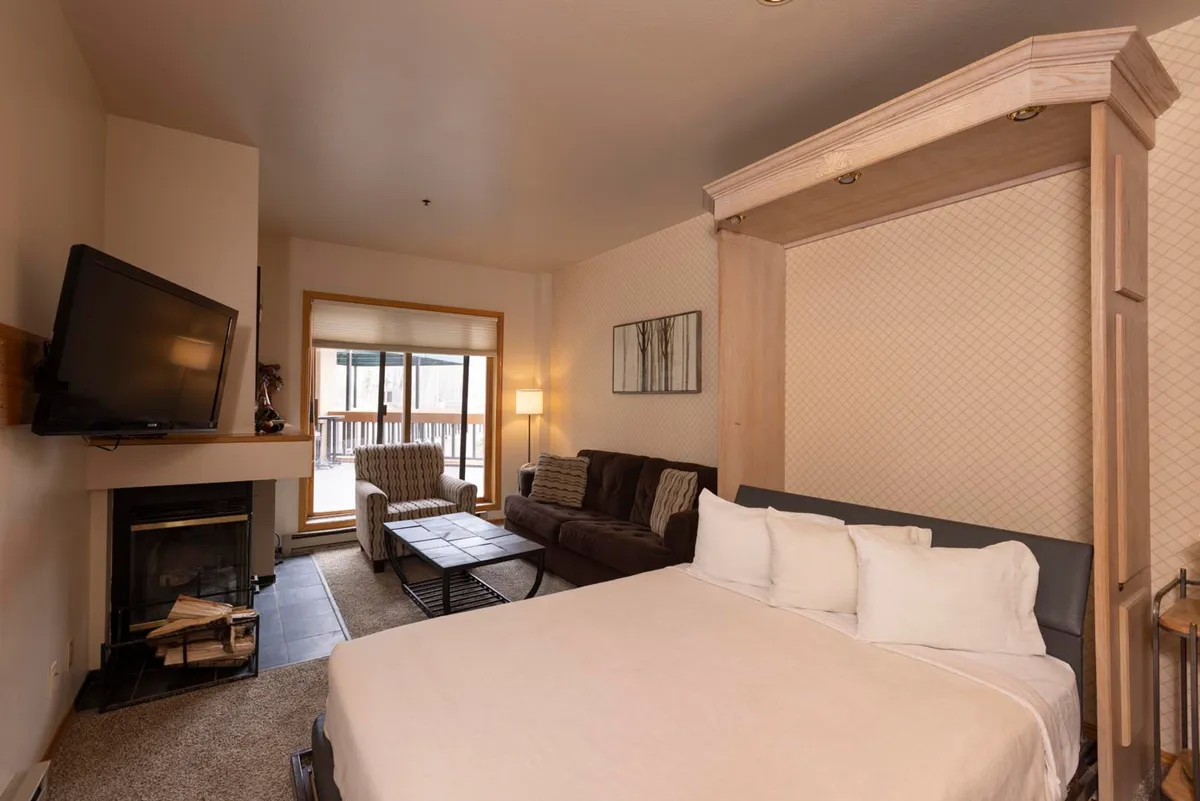 This inviting interior image showcases a well-appointed living area featuring a Murphy bed, sleeper sofa, fireplace, TV, and a window with views. The setting is warm and versatile, emphasizing both comfort and functionality. The presence of both a bed and sofa visually represents the flexible sleeping arrangements described in the section.